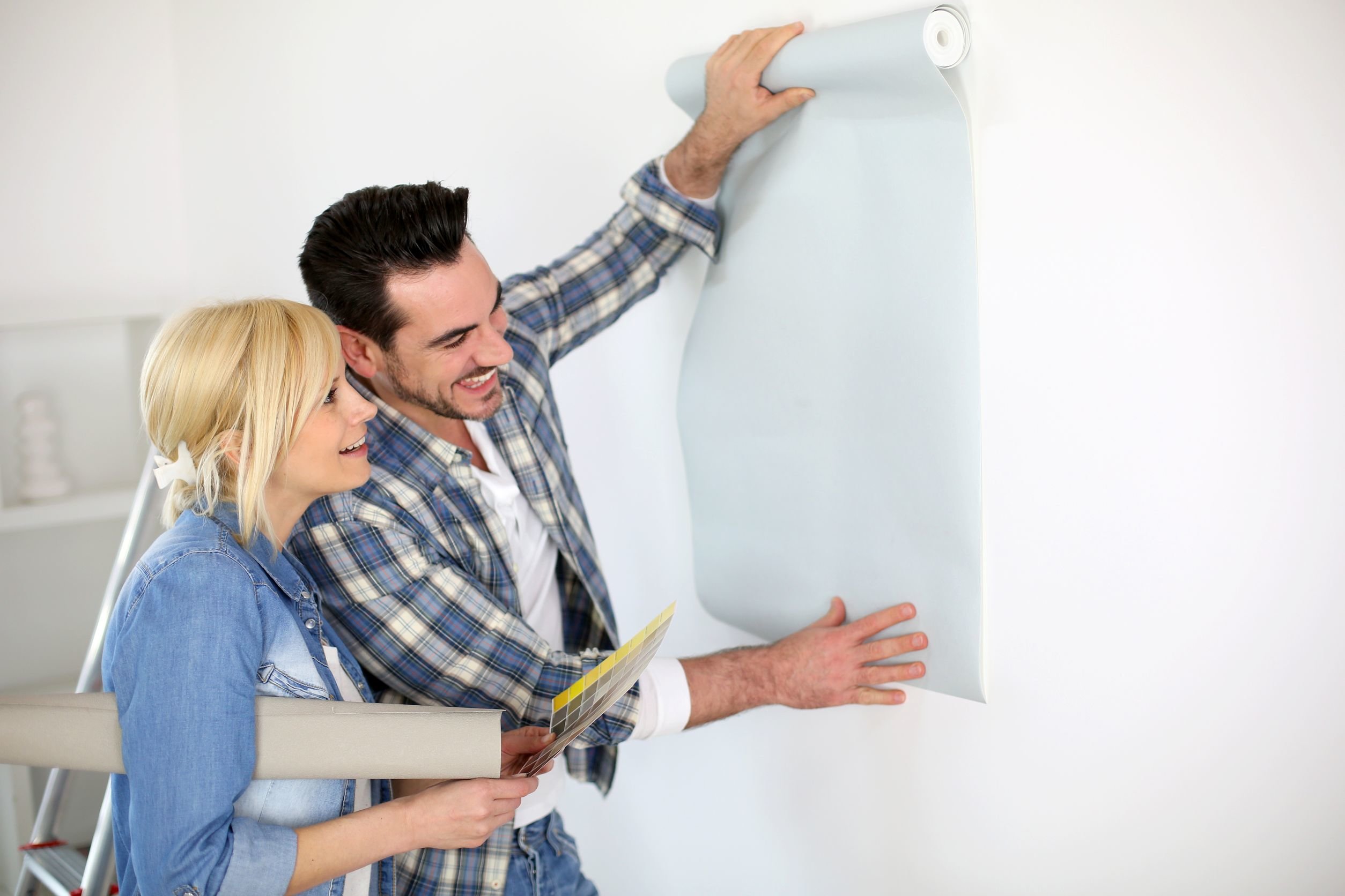 Junges Paar hält Tapete an die Wand um die Tauglichkeit zu prüfen